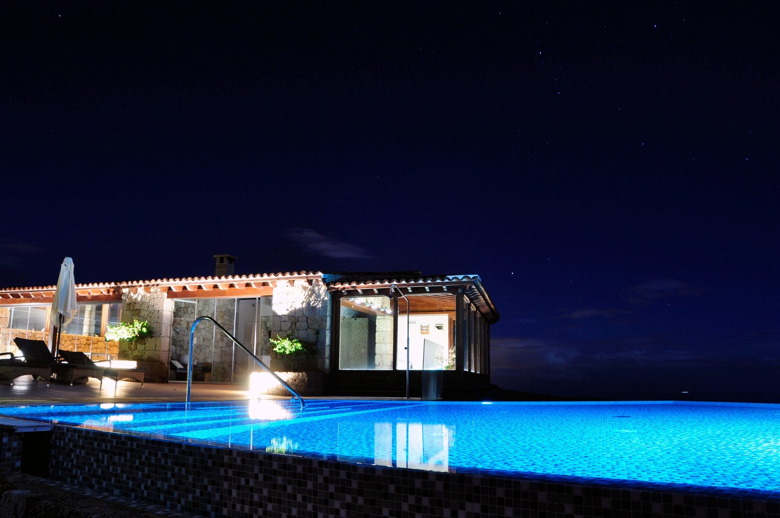 La piscina infinita climatizada iluminada por la noche en Las Casas del Camino.