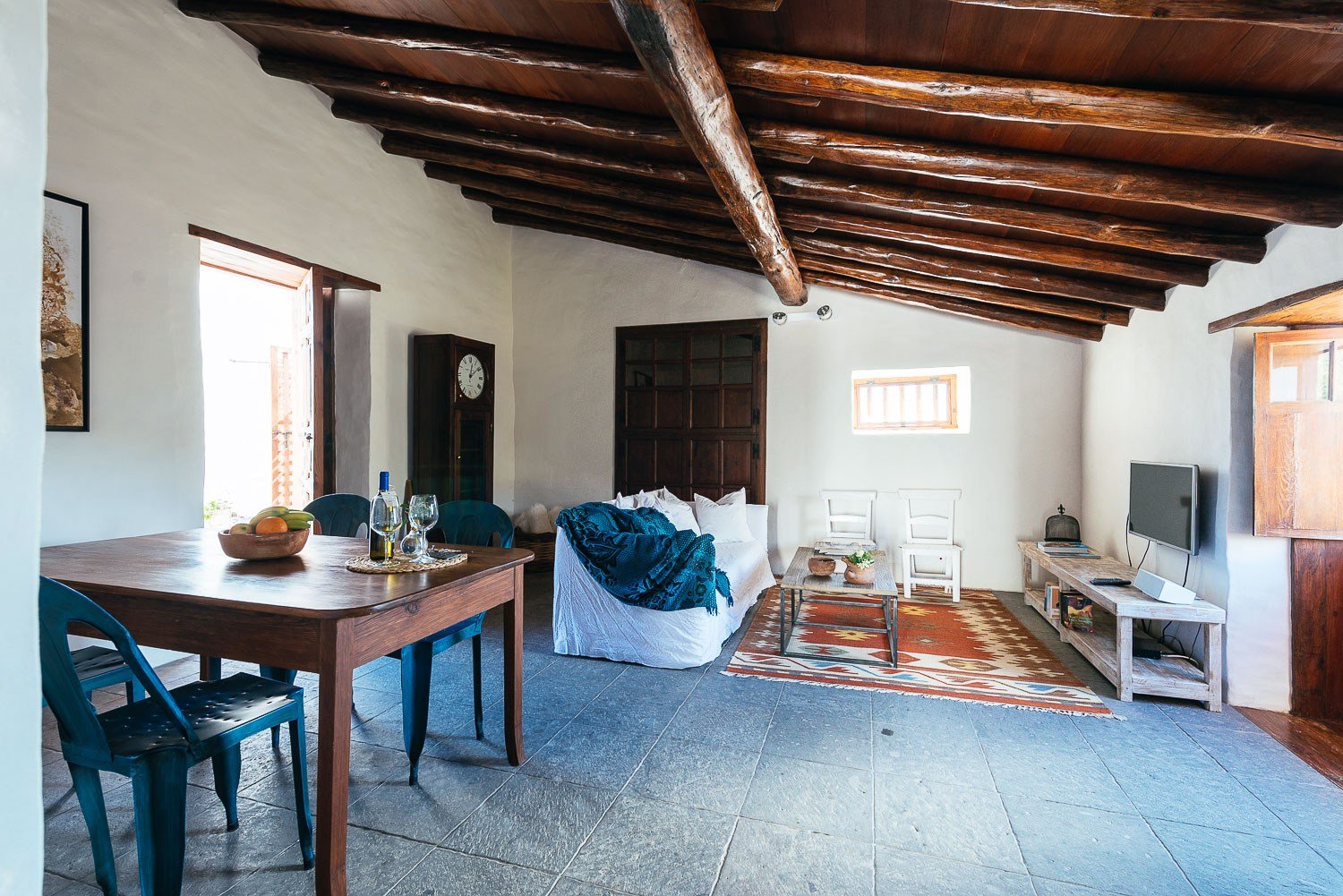 La zona del salón, completa con un sofá, televisión, mesa de comedor y elementos tradicionales canarios del Siglo XVII - La Casa del Alpendre.
